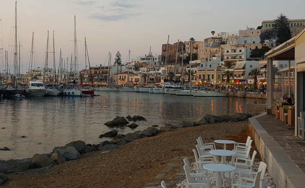Naxos Greece: Travel Guide 2023 4 A photo of sunset over Naxos Harbor with the boats in the harbor and restaurants along the shore